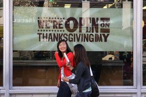 行人在旧金山的一家老海军商店进行感恩节日的广告。“border=
