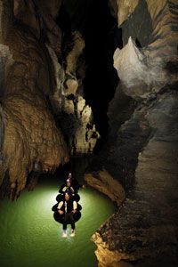 Three connected tubers drift along the Waitomo River, where the term "black water rafting" was coined.