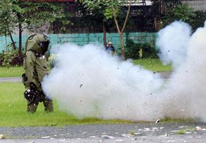 2003年10月，在菲律宾马尼拉的警察营地，一名身着防爆服的警察拆弹专家在一次爆炸试验中毫发无损。＂width=