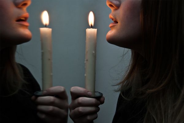 Woman holding candle up to mirror