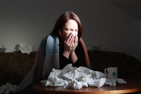 Woman blowing nose at table