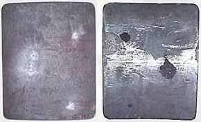 The front (left) and back (right) of a hard-armor steel plate. The plate has been shot with several different rifle rounds, all of which were deflected. The highest caliber round created a slight dent in the back of the plate, but none of the shots would have caused significant blunt trauma.
