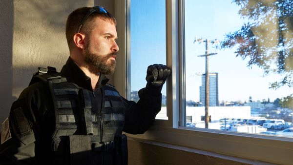 Man in body armor and bulletproof vest gazing out the window