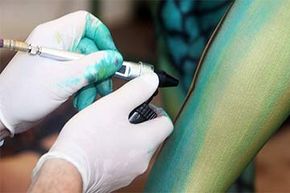An artist uses an airbrush pistol to paint a model at the World Bodypainting Festival.