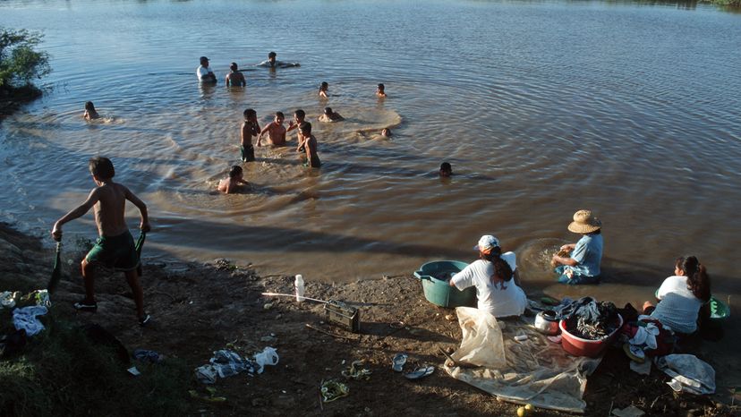 人们在亚马逊河地区的游泳和洗衣服“border=
