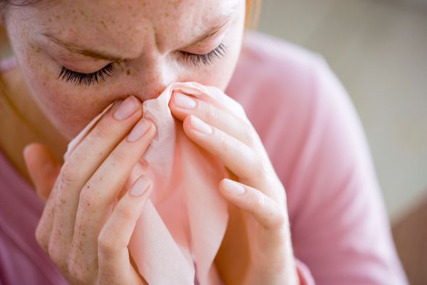 A woman blows her nose.