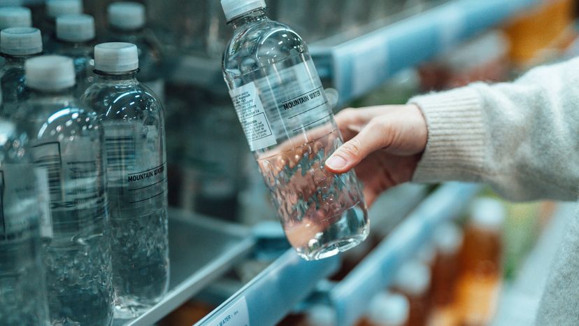 Woman Pulling Bottled Water from Supermarket Shelf