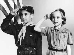 Boy Scout and Girl Scout salute the American flag, circa 1960s.
