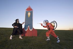 alien and spaceman fight in front of rocket ship