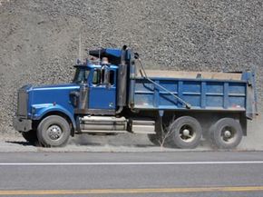 A dump truck driving beside a highway