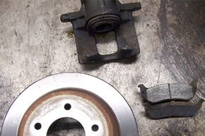 This photo shows a typical disc brake assembly with rotor, pads and caliper. This assembly was replaced after the caliper froze and the pads wore down to almost no thickness. Heat warped the rotor and prevented the brakes from working effectively.