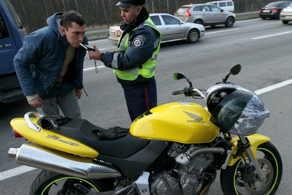 A motorcycle rider blows in to an alcohol breathalyzer.