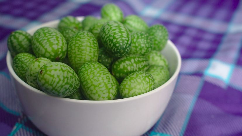 Cucamelon fruits in a white bowl on a plaid tablecloth.