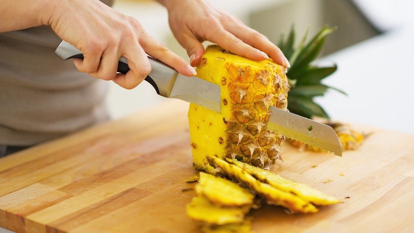 person cutting pineapple