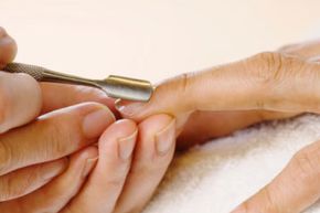 Woman receiving manicure, cuticles are pushed back.