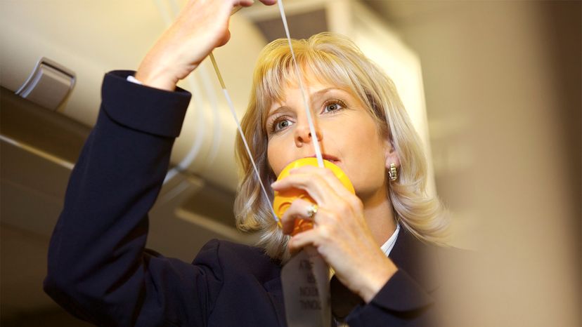 A stewardess demonstrates putting on the air mask if the pressure in the cabin falls.