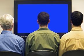 Three men watching a TV.