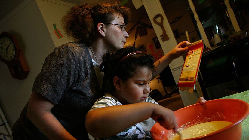 Christina Hall looks over the instructions on the back of the cake mix box, as her daughter Rosita Navarro, 7, stirs the batter for the young girl's birthday cake at their home in Alexandria, Virginia. Nikki Kahn/The Washington Post/Getty Images