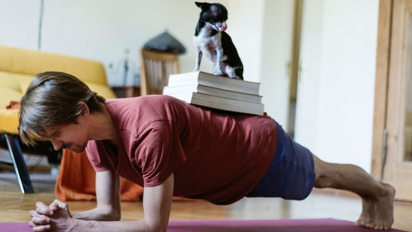 man doing planks with dog and book