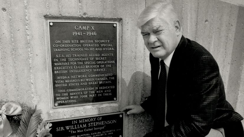 Former Whitby, Ontario, Mayor Bob Attersley kneels next to a Camp X plaque. It was top secret in its heyday, but Camp X is now recognized as a notable historical site. Paul Irish/Toronto Star via Getty Images