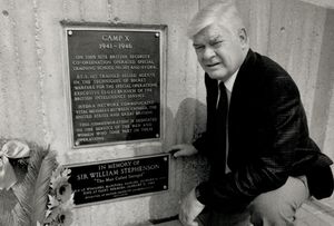 Whitby Mayor Bob Attersley kneeling next to Camp X plaque