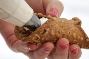 Cannoli being filled with a pastry bag