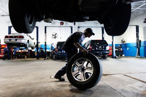 A mechanic rolls a tire