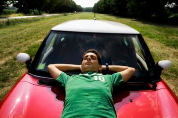man relaxing on hood of red mini cooper
