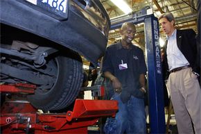 Sen. John Kerry chats with a student working on an automobile wheel alignment during Kerry’s 2004 bid for the U.S. presidency.