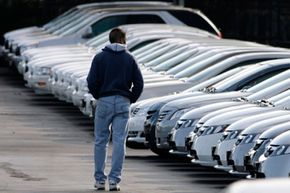 A shopper scans a long line of unsold General Motors lease-return vehicles on the lot of a Pontiac-GMC dealership in Aurora, Colo.