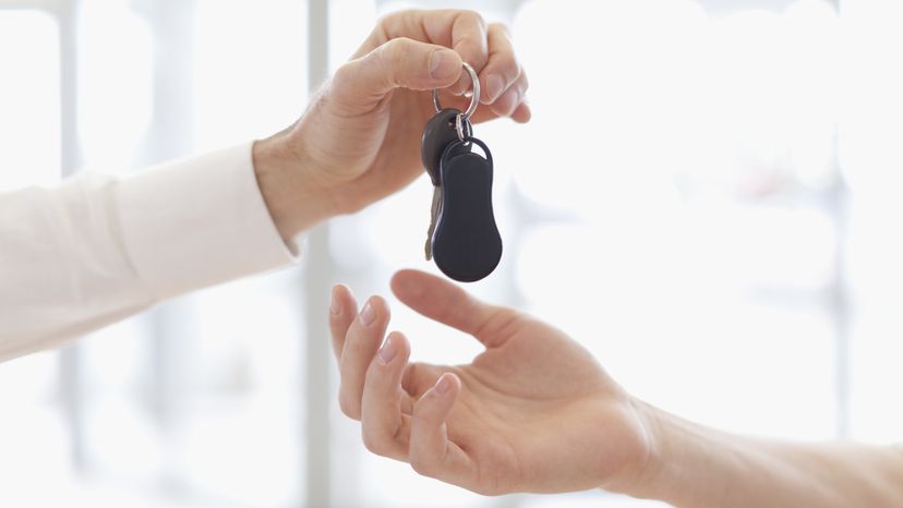 A person giving another person a car key