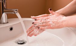 Person washing hands in sink. 