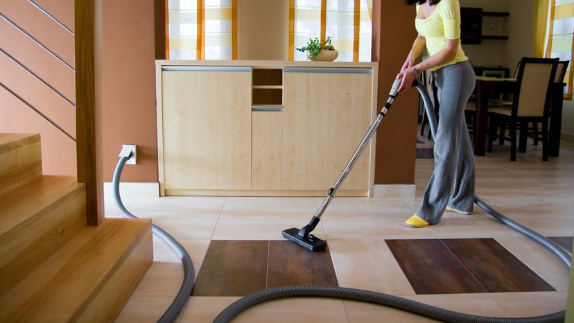 Woman vacuuming house using a central vacuum system