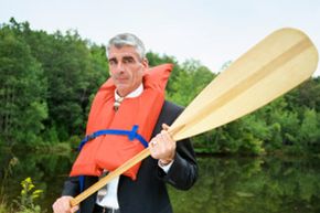 man wearing life vest and wielding an oar