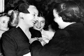 Eva Peron (left) being presented with an insignia by the volunteer workers of the Institute for Work of Argentina.