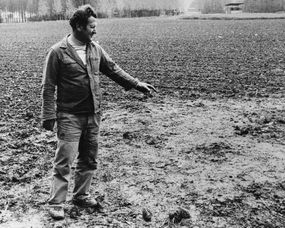 a man points to a spot in a field