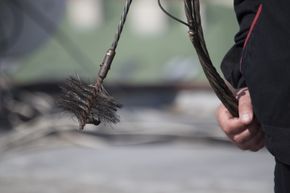 Someone using a chimney sweep tool.