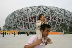 北京图片库A man poses with his baby outside of the National Stadium or "Bird's Nest" in Beijing. China has experienced a surge in Olympic-themed baby names. See more pictures of Beijing.”width=