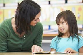 A teacher reads with a student.