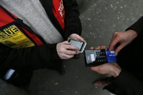 A street newspaper vendor (L) uses his Chip and PIN device outside the South Kensington Tube Station in London, 2013. Chip and PIN cards are widely used in Europe.