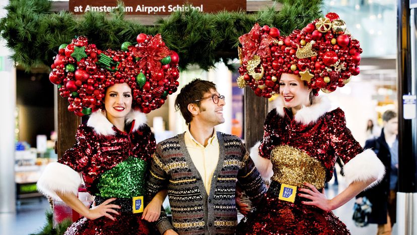 Two women in Christmas costumes pose with a tourist.