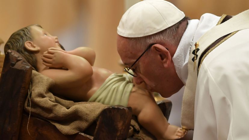 Pope Francis kisses a figurine of baby Jesus.