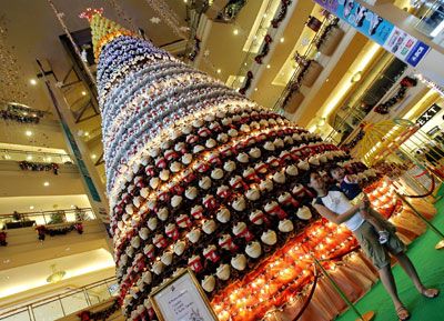 A woman holds a child as they pose for photo in front of a Christmas tree made out of toys at a shopping mall in Jakarta, Indonesia on Dec. 21, 2006.