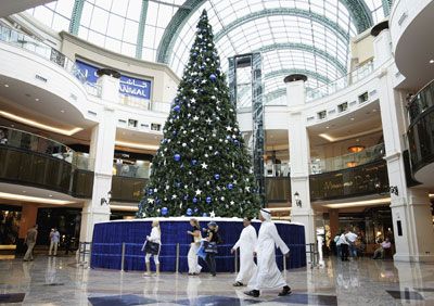 Men in traditional clothes walk past a giant Christmas tree in the Mall of the Emirates, one of the largest malls in the world on Dec. 12, 2006 in Dubai, United Arab Emirates.