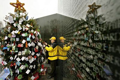 2006年12月21日，在华盛顿，来自弗吉尼亚州阿灵顿市的越战老兵丹·柯比正在帮助装饰越战老兵纪念碑上的圣诞树”border=