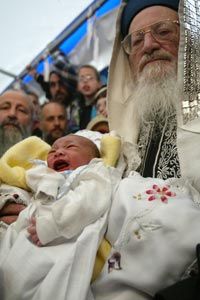 Rabbi Mordechi Eliyaho holds eight-day-old Adam as he and others participate in a circumcision ceremony during a sit-in in front of the Knesset.
