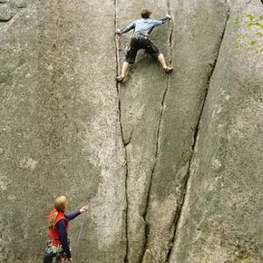 上图中攀岩者使用绳索和钩子的攀岩方式被归类为辅助攀岩。＂width=