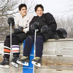 Two boys in ice hockey uniforms and gear.