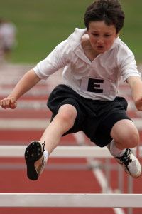 Youth jumping hurdle.