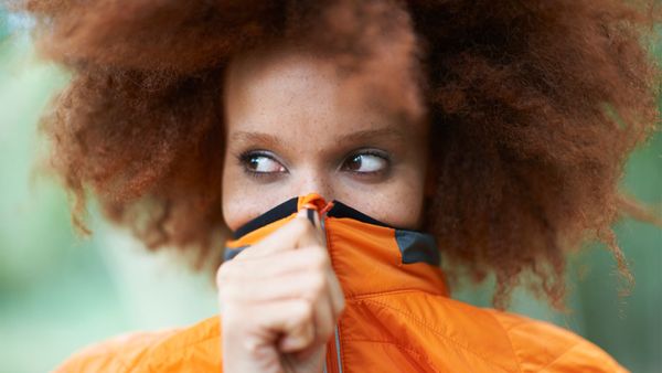 woman with orange sweater pulled over mouth